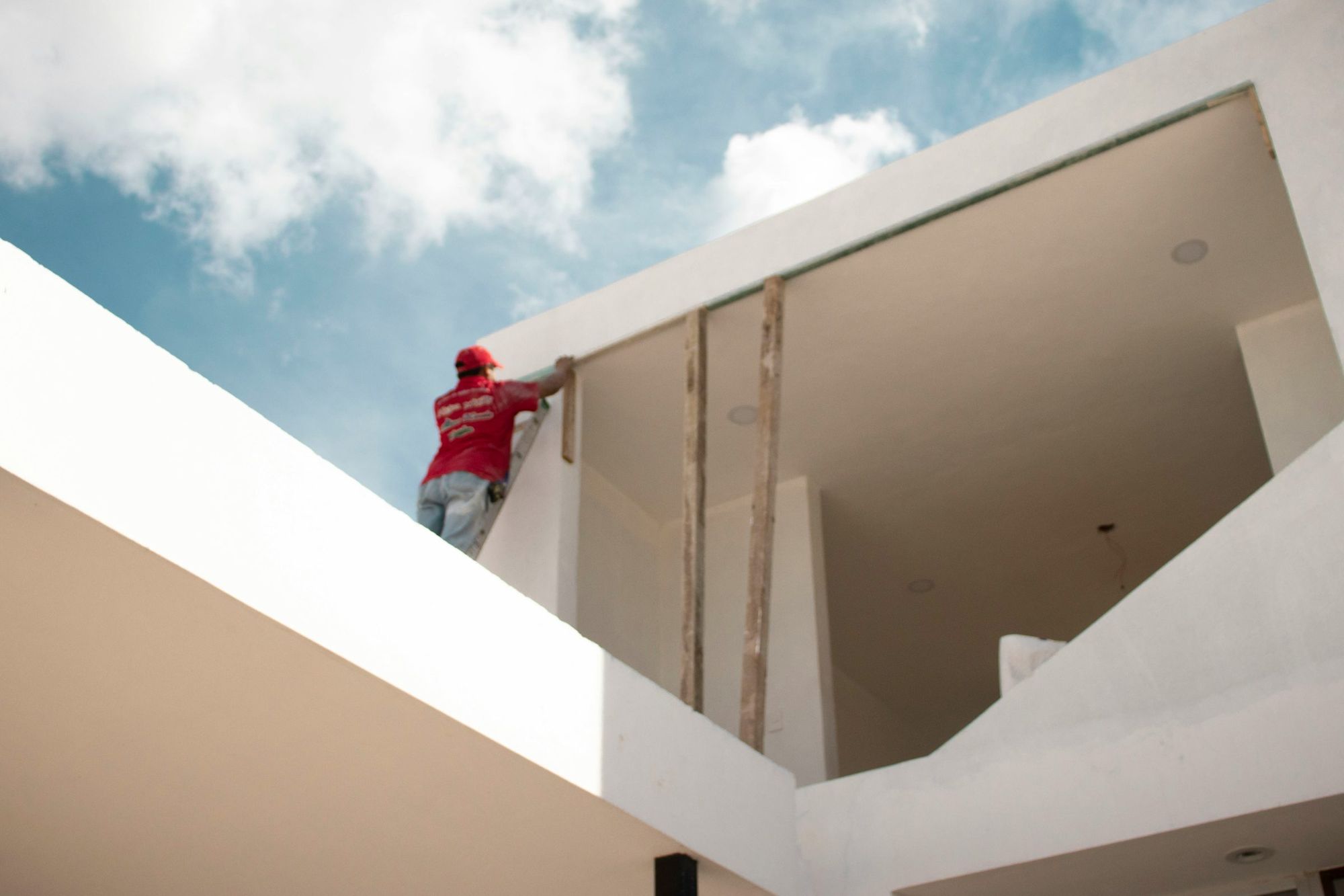 Profissional trabalhando na fachada branca de uma casa em reforma