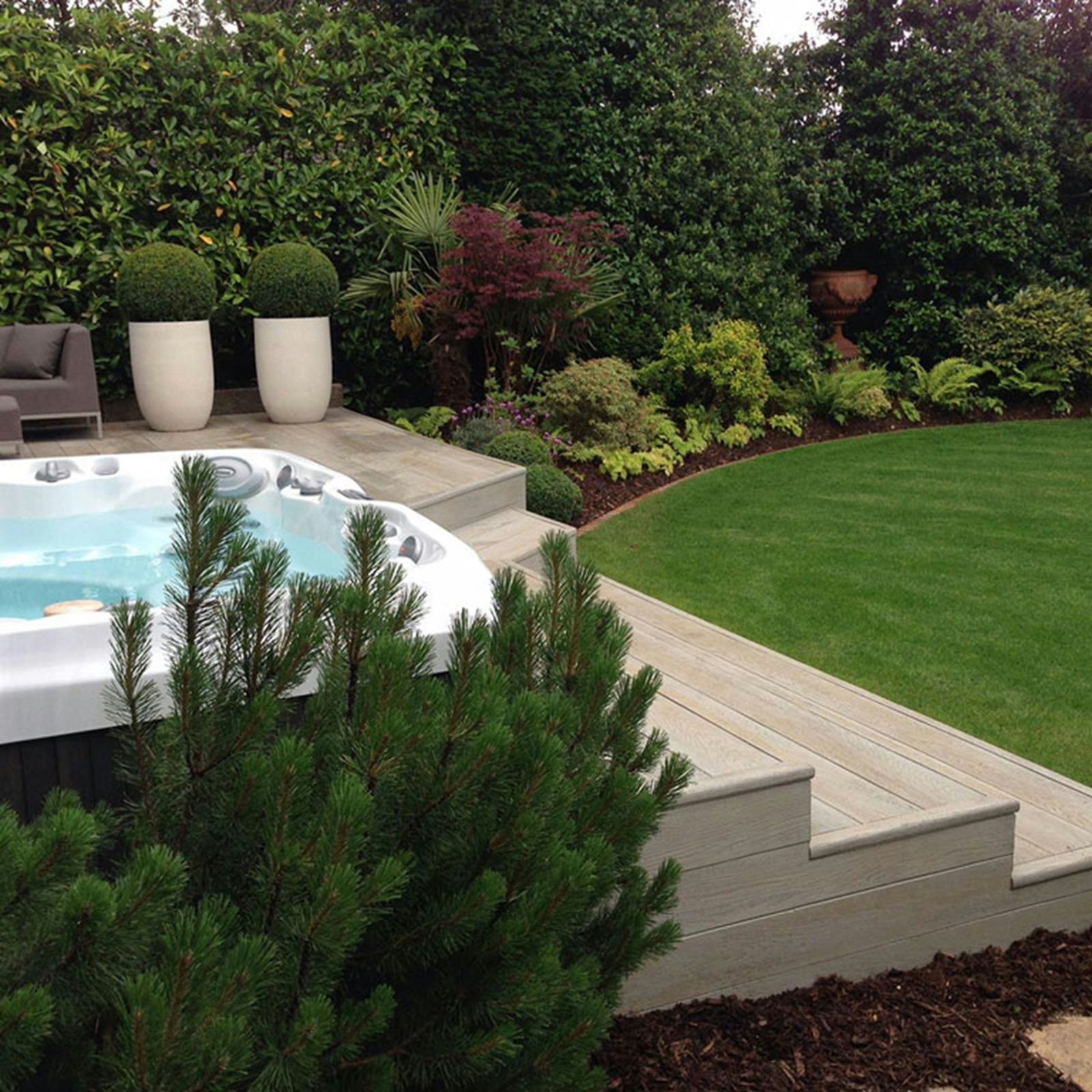 Deck de madeira com jacuzzi cercado por jardim