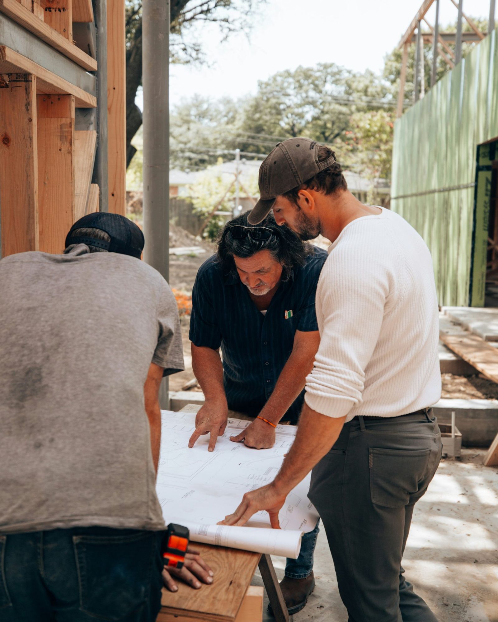 Três profissionais conferindo a planta do projeto na obra