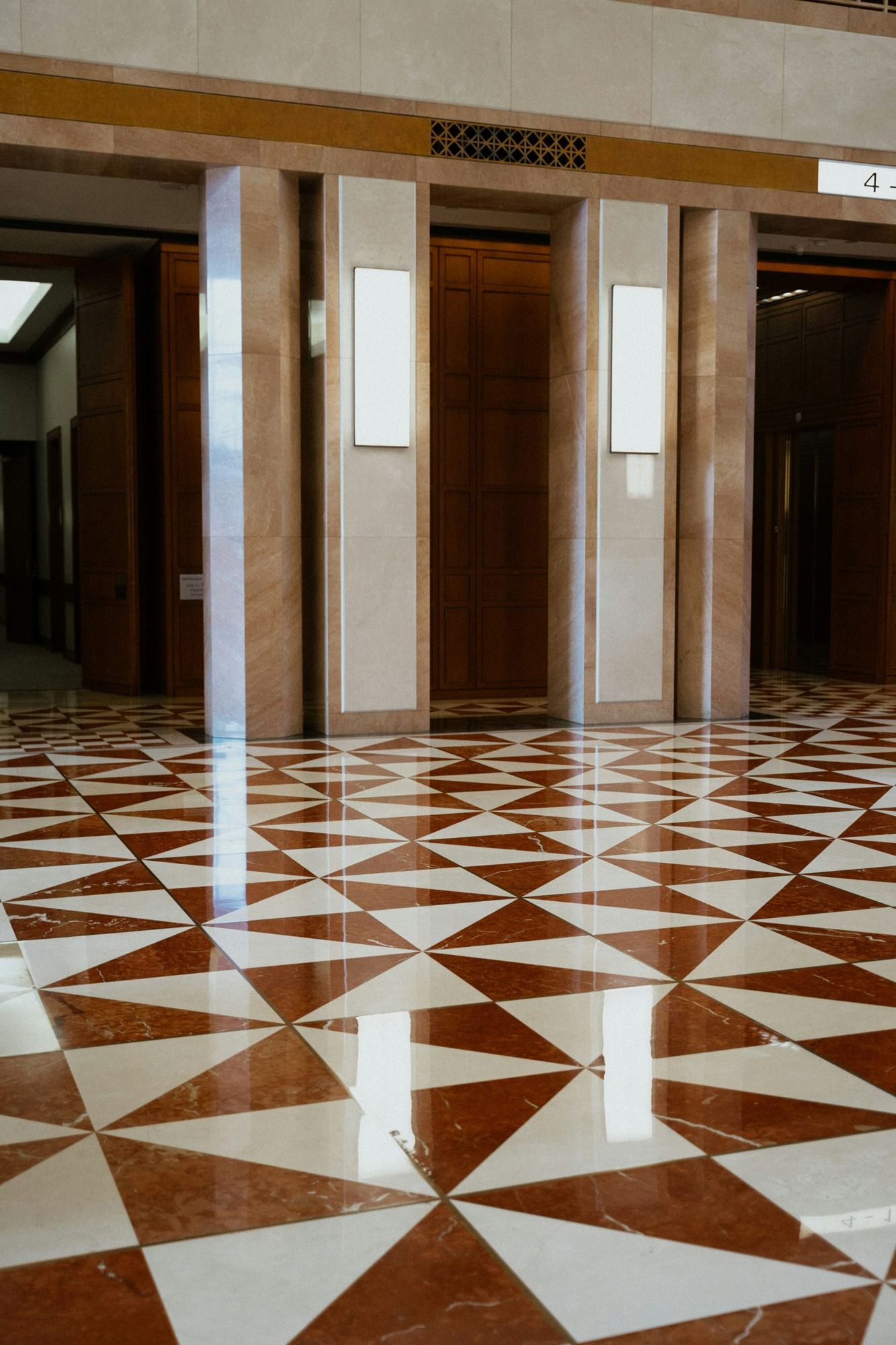 Piso polido em mármore vermelho e branco com desenho geométrico em um saguão