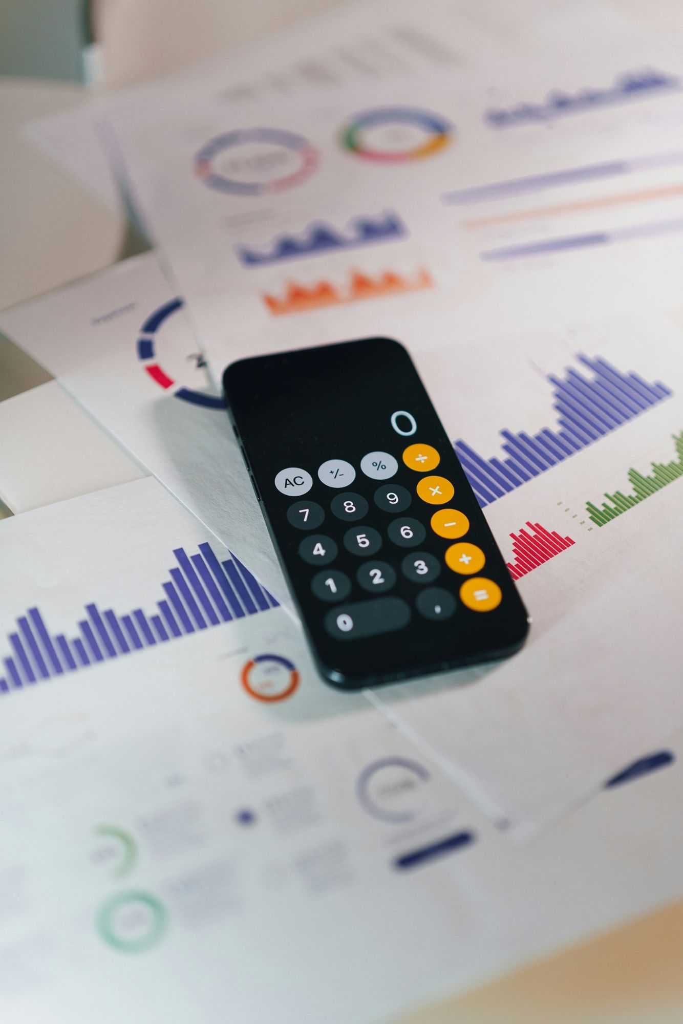 Celular com calculadora sobre relatórios com gráficos de orçamento